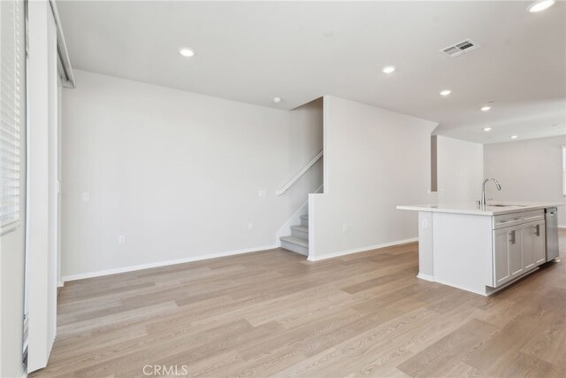 2718 Crozier Ct, Pomona, CA 91767 - kitchen featuring a sink, light wood-type flooring, light countertops, a center island with sink, and baseboards