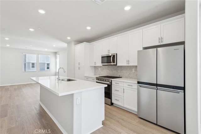 2718 Crozier Ct, Pomona, CA 91767 - kitchen with stainless steel appliances, a sink, white cabinets, a center island with sink, and tasteful backsplash