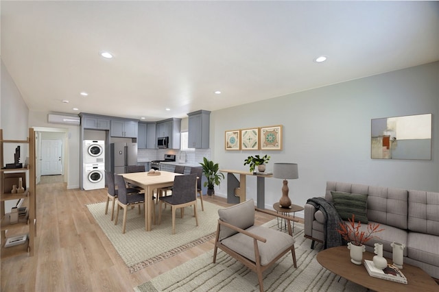 dining area featuring stacked washer and clothes dryer, a wall unit AC, and light hardwood / wood-style floors