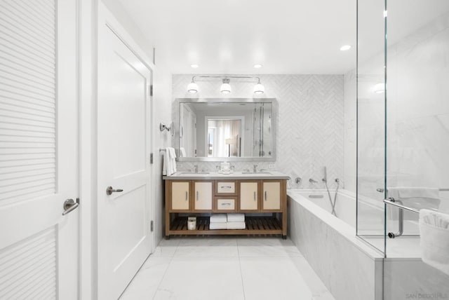 bathroom featuring a relaxing tiled tub, vanity, and tile walls