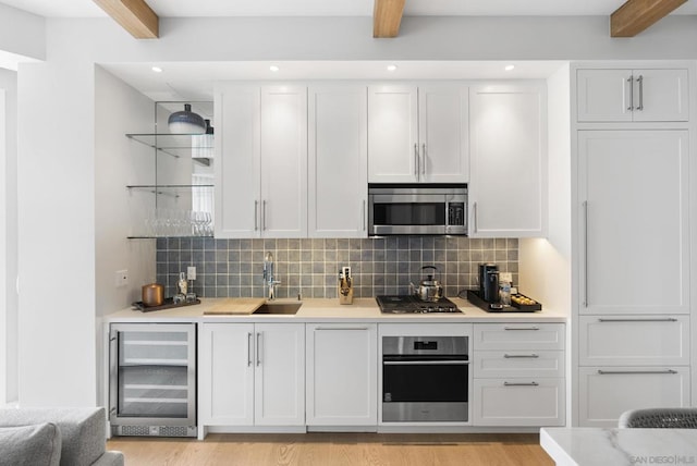 kitchen featuring stainless steel appliances, white cabinetry, beverage cooler, and beamed ceiling