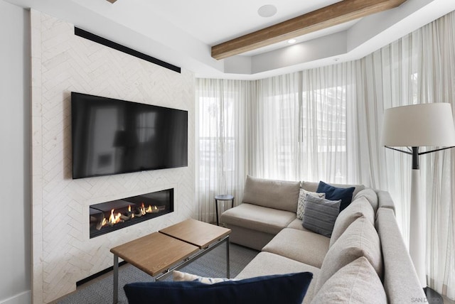 living room featuring beamed ceiling and a large fireplace