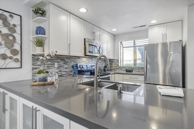 kitchen with tasteful backsplash, white cabinetry, appliances with stainless steel finishes, and sink