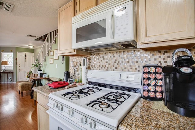 kitchen with backsplash, hardwood / wood-style flooring, light brown cabinets, a textured ceiling, and white appliances