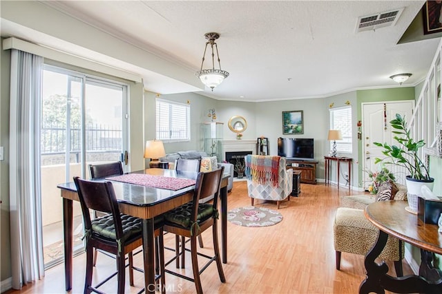 dining space with crown molding and light wood-type flooring