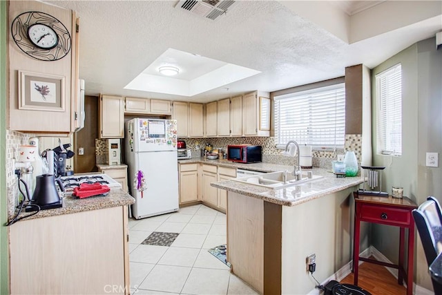 kitchen with backsplash, white refrigerator, kitchen peninsula, a raised ceiling, and light brown cabinets