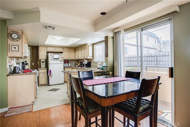 tiled dining room with a raised ceiling and ornamental molding