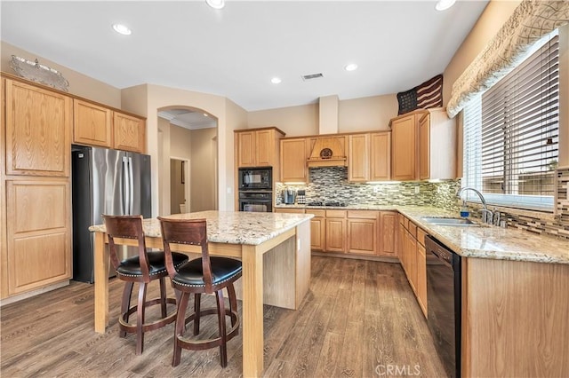 kitchen with sink, light hardwood / wood-style flooring, light stone counters, and black appliances