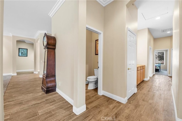 hall with ornamental molding and light hardwood / wood-style floors