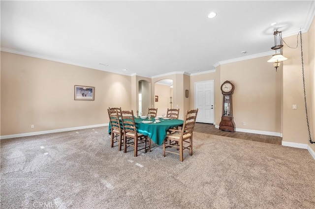 carpeted dining space with crown molding