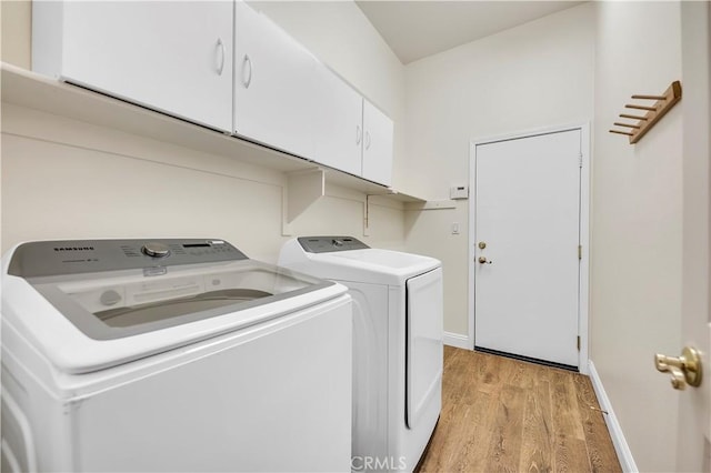 clothes washing area featuring cabinets, separate washer and dryer, and light hardwood / wood-style flooring