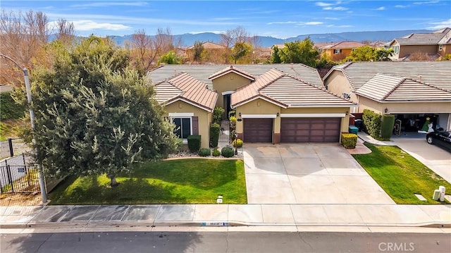 view of front facade featuring a garage, a mountain view, and a front yard