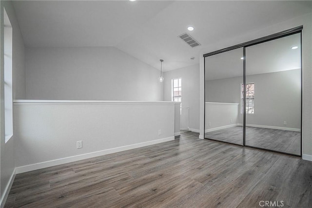 unfurnished bedroom with wood-type flooring, lofted ceiling, and a closet