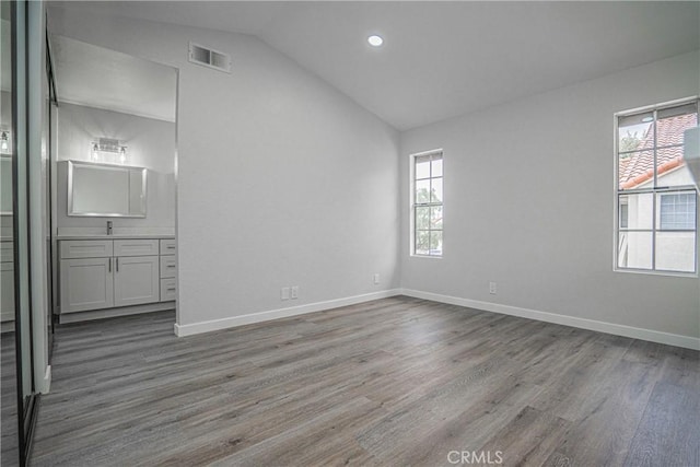 spare room featuring a healthy amount of sunlight, vaulted ceiling, and hardwood / wood-style floors