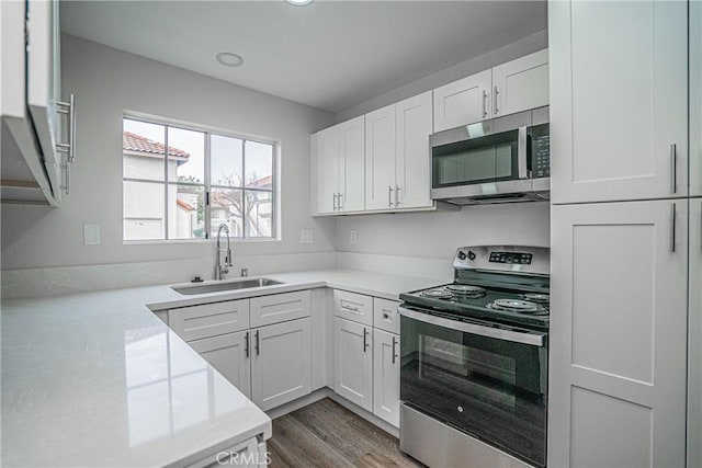 kitchen with stainless steel appliances, white cabinetry, sink, and dark hardwood / wood-style flooring