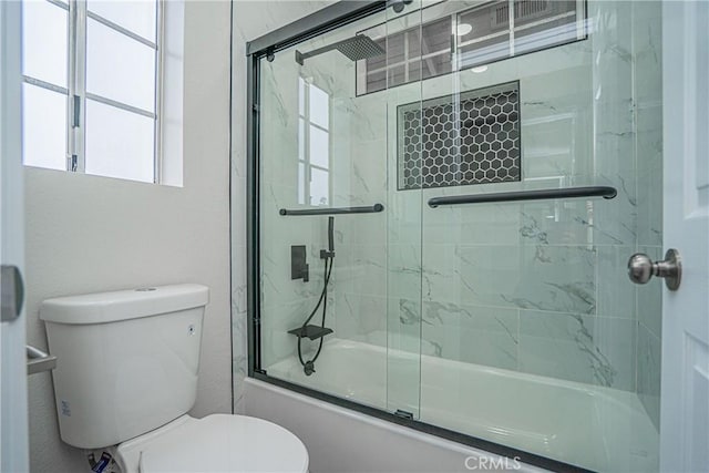 bathroom with toilet and combined bath / shower with glass door