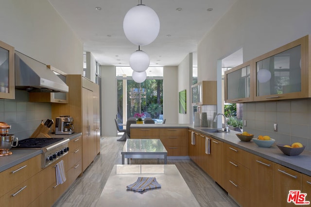 kitchen featuring pendant lighting, sink, decorative backsplash, kitchen peninsula, and stainless steel gas stovetop