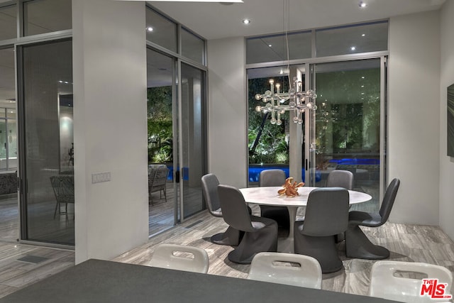 dining area featuring floor to ceiling windows, a chandelier, and light hardwood / wood-style flooring