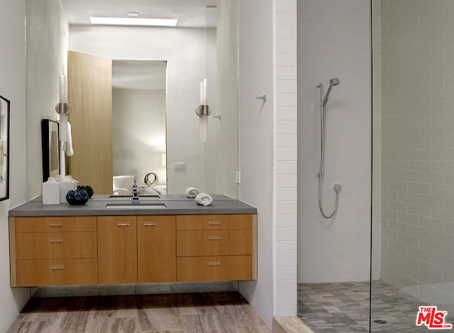 bathroom featuring vanity, hardwood / wood-style floors, and a tile shower