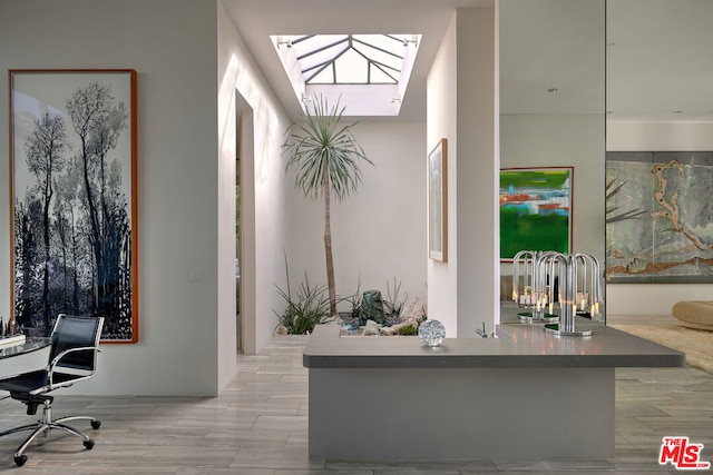 home office featuring light hardwood / wood-style flooring and a skylight