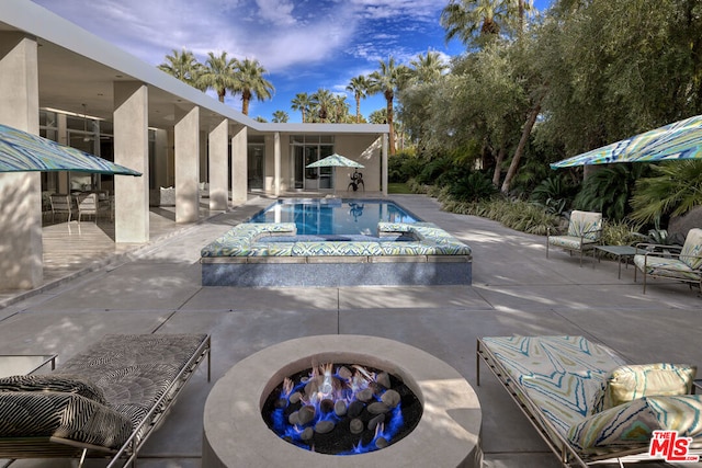 view of pool with an outdoor fire pit and a patio