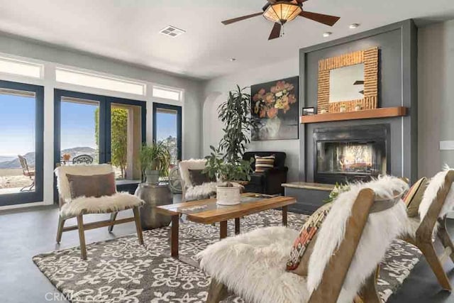 sitting room with a large fireplace and ceiling fan