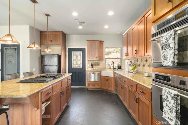 kitchen featuring sink, appliances with stainless steel finishes, a center island, light stone countertops, and decorative light fixtures