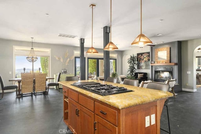 kitchen with a center island, stainless steel gas cooktop, a kitchen breakfast bar, and decorative light fixtures