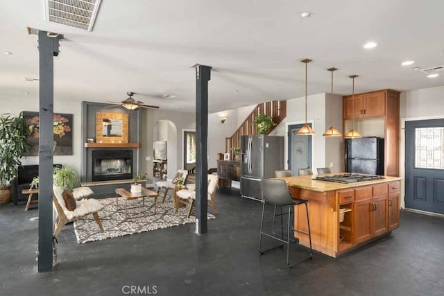 kitchen with appliances with stainless steel finishes, a kitchen breakfast bar, hanging light fixtures, a center island, and ceiling fan