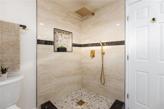 bathroom with a tile shower and toilet