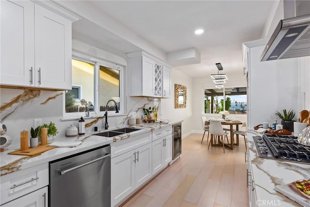 kitchen featuring stainless steel appliances, light stone countertops, sink, and white cabinets