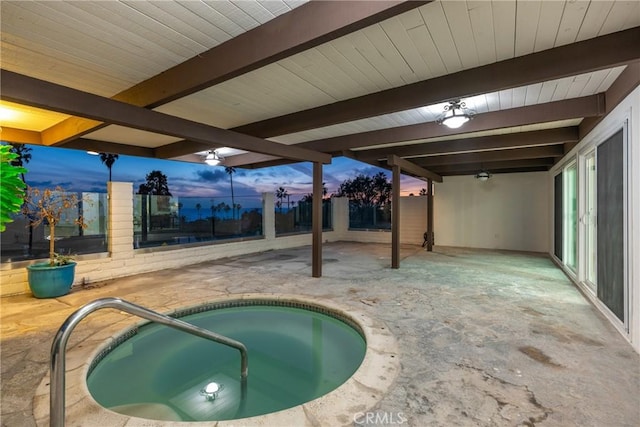 pool at dusk with a patio area and an in ground hot tub