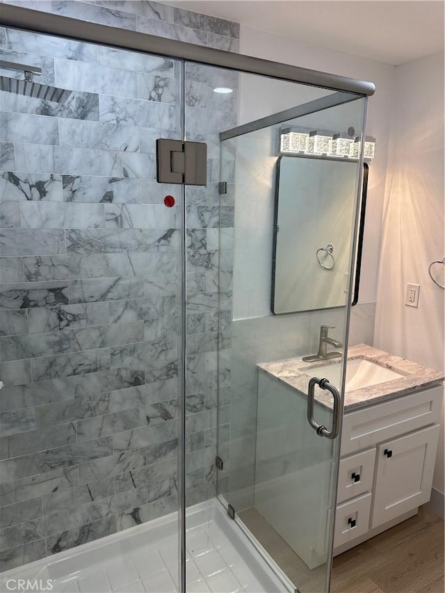 bathroom featuring walk in shower, vanity, and hardwood / wood-style floors