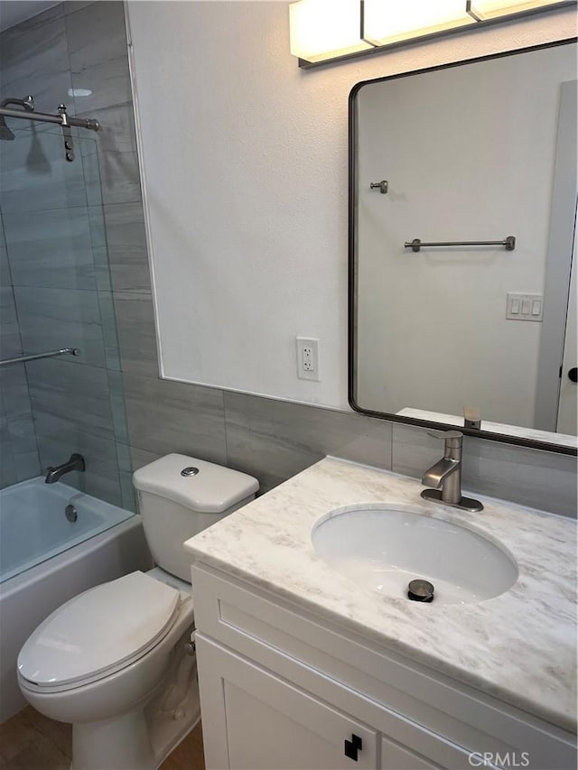 full bathroom featuring vanity, bath / shower combo with glass door, tile walls, and toilet