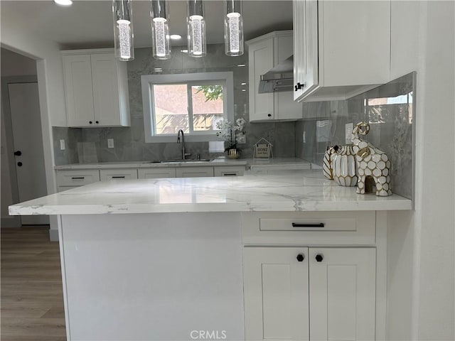 kitchen featuring sink, white cabinetry, pendant lighting, light stone countertops, and backsplash