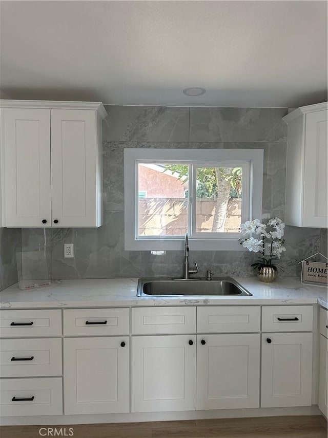 kitchen featuring light stone countertops, sink, decorative backsplash, and white cabinets