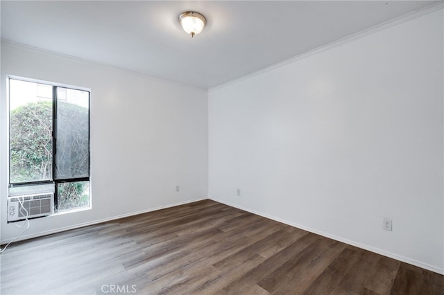 empty room featuring cooling unit, baseboards, wood finished floors, and ornamental molding