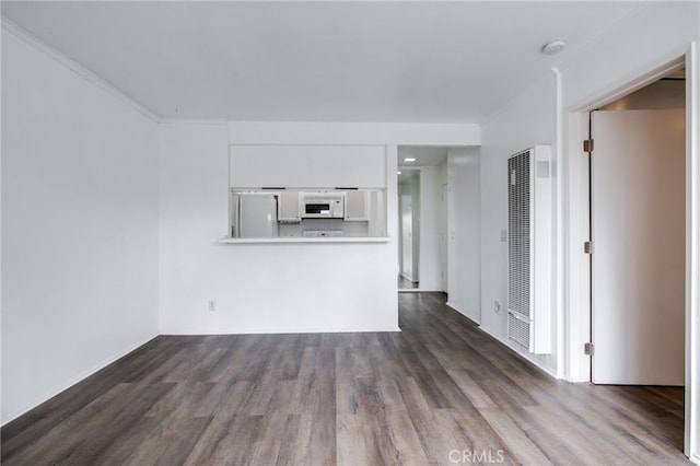 unfurnished living room with dark wood-style floors and a heating unit