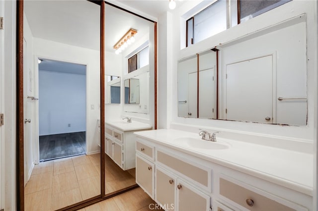 bathroom with two vanities, wood finished floors, and a sink