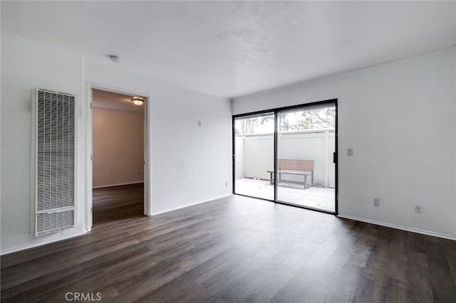 empty room featuring baseboards, wood finished floors, and a heating unit