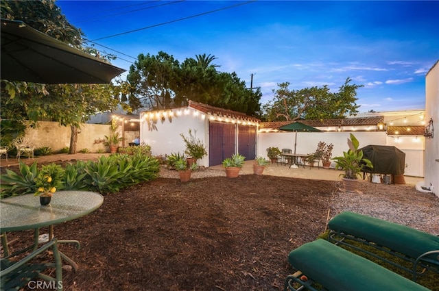 yard at dusk featuring a storage shed and a patio area