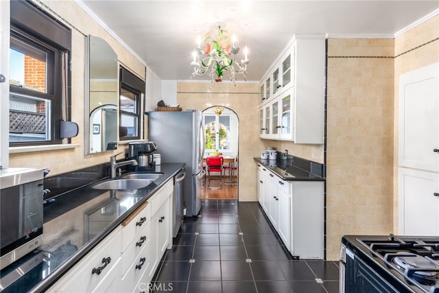 kitchen with sink, stainless steel appliances, a chandelier, and white cabinets