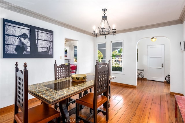 dining room with hardwood / wood-style flooring, ornamental molding, and an inviting chandelier