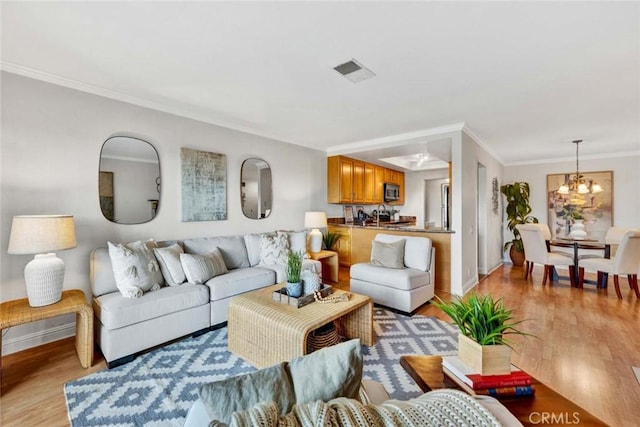 living room with a notable chandelier, light hardwood / wood-style flooring, and ornamental molding