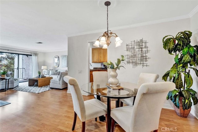 dining area featuring an inviting chandelier, ornamental molding, and light hardwood / wood-style floors