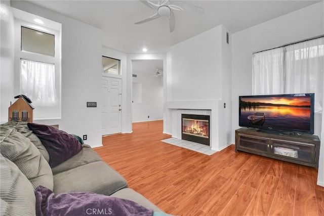 living room with visible vents, wood finished floors, a ceiling fan, and a tile fireplace