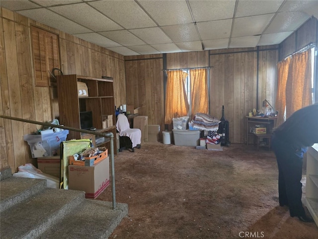 miscellaneous room with a drop ceiling, wood walls, and carpet flooring