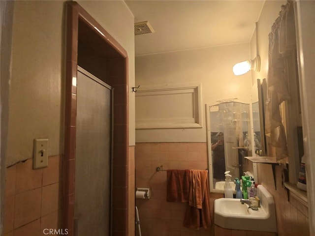 full bathroom with a sink, visible vents, tile walls, and a shower stall