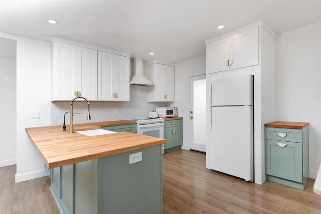 kitchen featuring wood counters, sink, green cabinets, wall chimney range hood, and white appliances