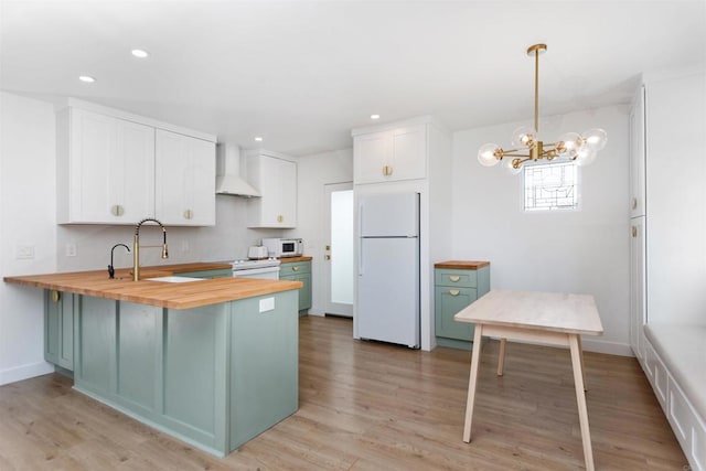 kitchen featuring pendant lighting, white cabinetry, wooden counters, white appliances, and wall chimney exhaust hood